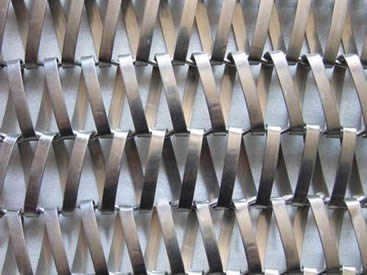 A piece of stainless steel conveyor belt mesh on the gray background.