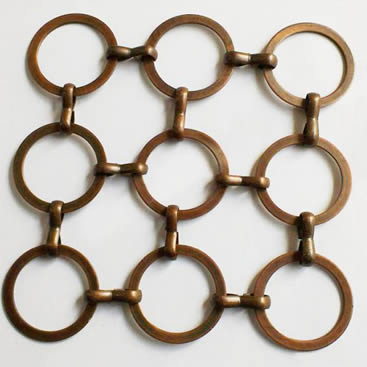 A piece of copper S hook metal ring mesh with flat wire on the gray background.