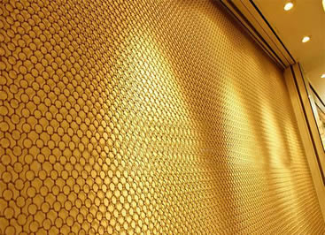 A piece of brass metal ring mesh is covering the wall.