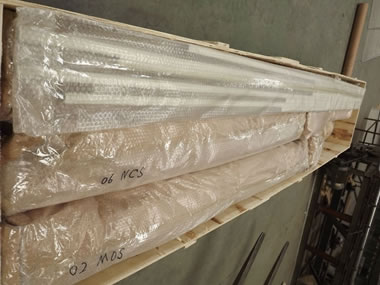 Several rolls of metal coil drapery with plastic film are in the wooden case.