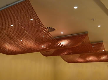 Copper color aluminum chain curtain is installed on the ceilings with a wave design.