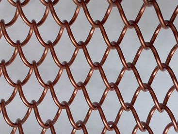 A piece of copper metal coil drapery on the gray background.