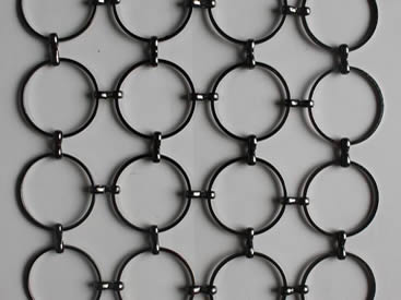 A piece of black S hook metal ring mesh on the gray background.