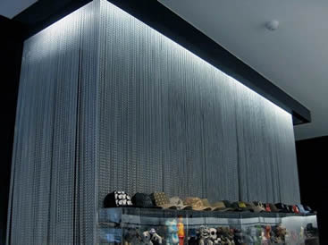 Several lines of aluminum chain curtains are installed on the wall behind of the shelf.