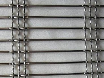 A piece of stainless steel crimped architectural mesh on the gray background.