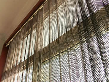 Metal coil drapery is installed on the windows and some sunlight comes into the room.